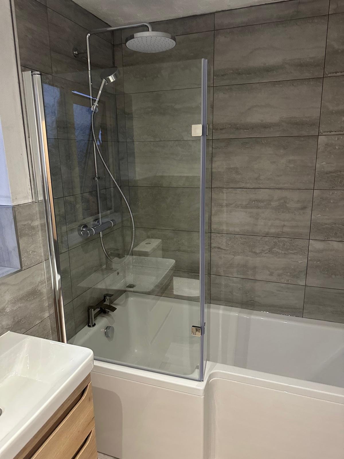 Completed bathroom with a rainfall shower over the bath and a glass screen