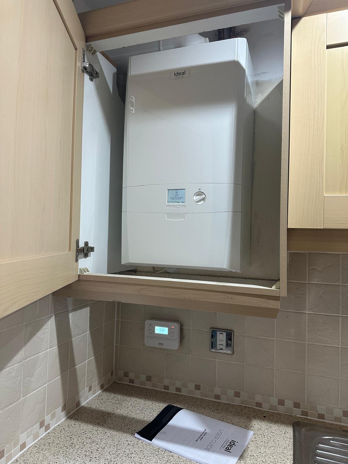 Ideal boiler being serviced inside a kitchen unit by a Gas Safe registered engineer