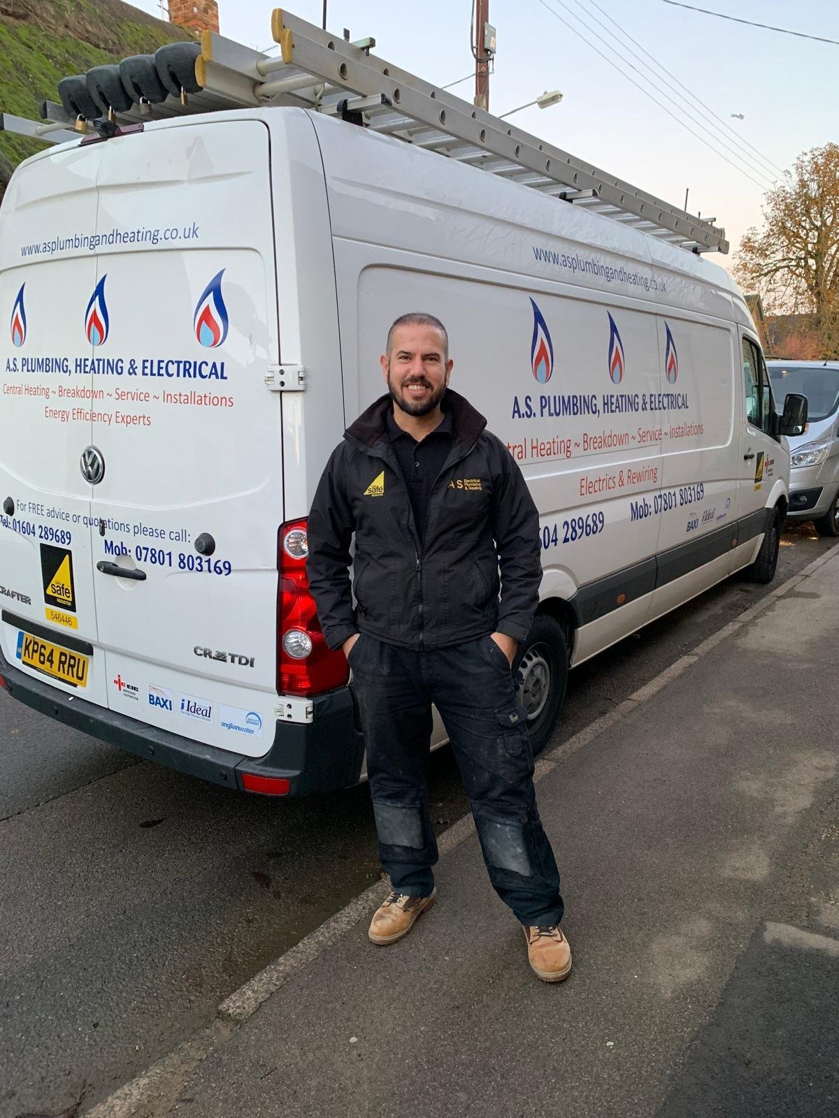 Service technician standing in front of a white plumbing and heating van with company branding and logos